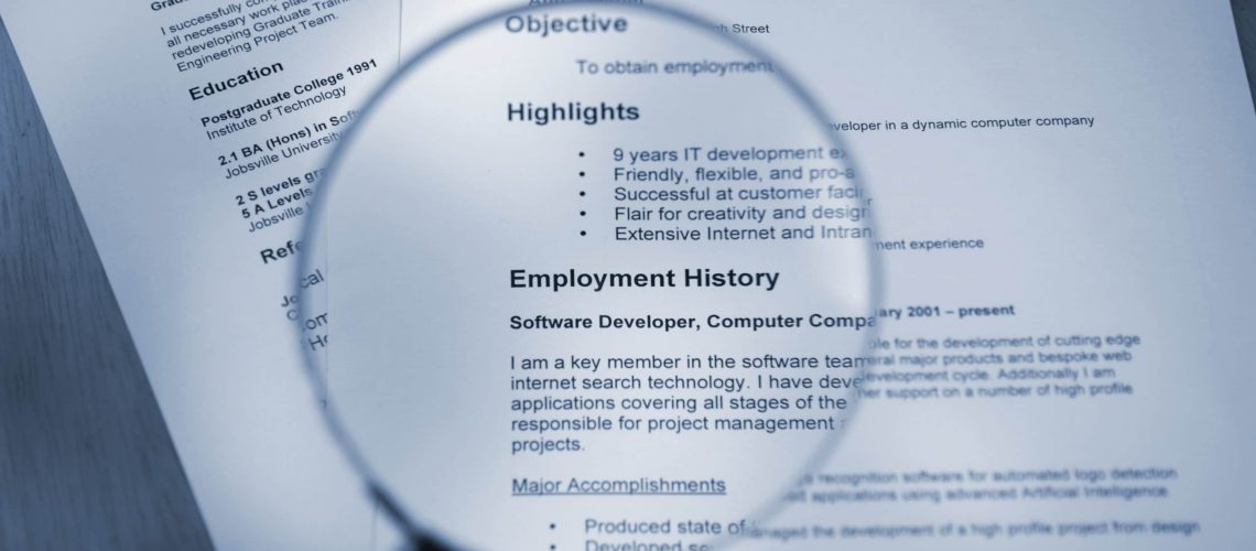 blue toned selective focus shot of resume and magnifying glass